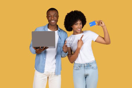 Téléchargez les photos : Un heureux couple afro-américain s'engageant avec un ordinateur portable et une carte de crédit, gérant probablement les finances ou les achats - en image libre de droit