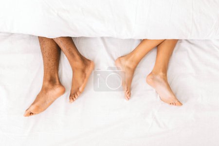 Téléchargez les photos : Couple endormi. pieds nus mâles et femelles sous la couette couchée sur le lit séparément, vue du dessus - en image libre de droit