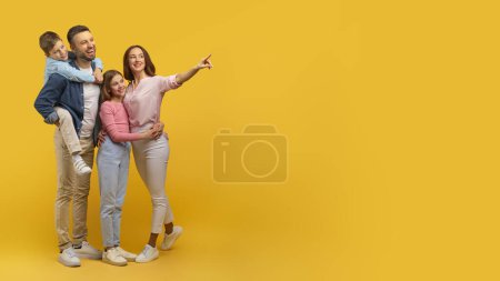 Téléchargez les photos : Une famille de quatre personnes avec deux enfants posant joyeusement sur un fond jaune vif, mettant en valeur la chaleur et la convivialité - en image libre de droit