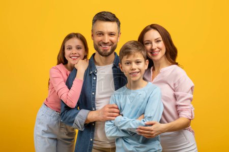 Photo for A content family of four clusters around a beaming father, creating a heartwarming image on yellow background - Royalty Free Image