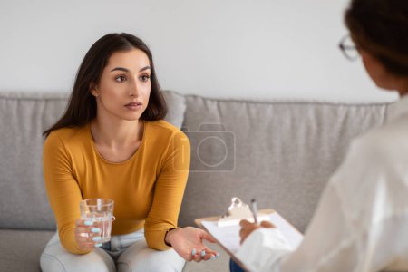 Téléchargez les photos : Une femme semble préoccupée en parlant et en faisant un geste à un conseiller pendant une séance de thérapie, l'eau potable - en image libre de droit
