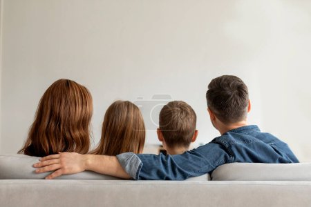 An image capture of a family moment where a family of four are sitting close on a sofa, showing unity and affection