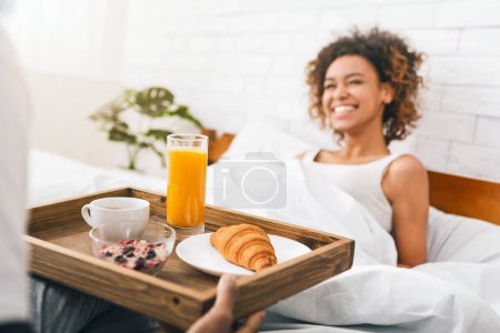 Photo for Lovely boyfriend bring some breakfast to his girlfriend in morning. Romance and kindness in relationship - Royalty Free Image
