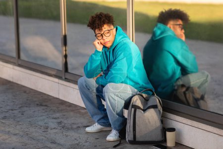Téléchargez les photos : Un jeune brésilien réfléchi s'assoit près d'une vitre, réfléchissant sur la vie alors que leur image leur renvoie, exsudant un sentiment d'introspection et de solitude - en image libre de droit