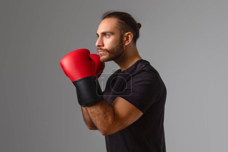 Serious man demonstrates readiness for a boxing session with a focused expression and gloves