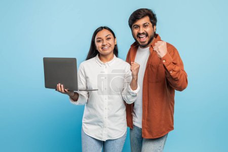 Indian couple celebrates a successful moment while holding a laptop, indicating a possible achievement online
