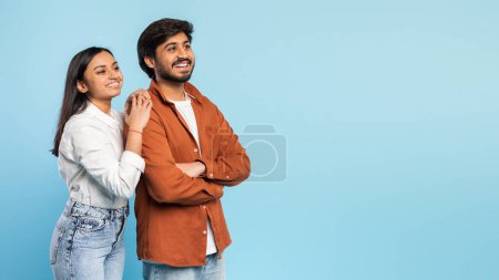 Photo for A young indian man and woman bonding, smiling joyfully with a clear blue background enhancing a vibrant and positive mood - Royalty Free Image