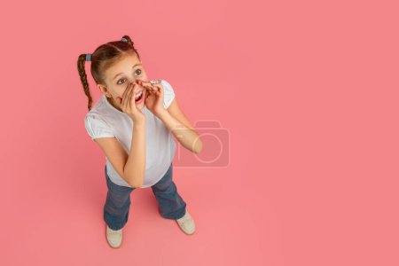A playful girl with braided hair holding hands next to her mouth, make announcement, copy space, high angle view