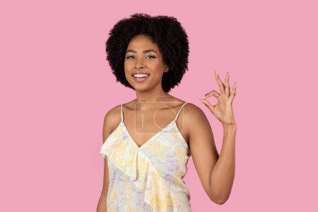 Confident African American woman gives a perfect OK hand sign, happy and smiling on pink background