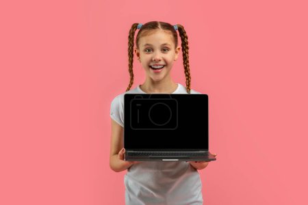 Foto de Chica sorprendida en blanco sostiene un portátil abierto con una pantalla en blanco, ideal para anuncios o conceptos de comunicación - Imagen libre de derechos