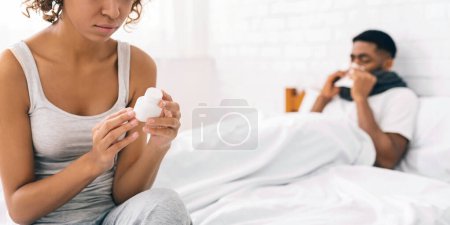 Téléchargez les photos : Aimer femme noire prendre soin de son mari malade, lecture prescription sur bouteille avec des pilules - en image libre de droit