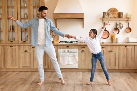 Téléchargez les photos : Père et fille partagent un moment ludique, dansant ensemble dans la cuisine familiale avec joie et bonheur - en image libre de droit