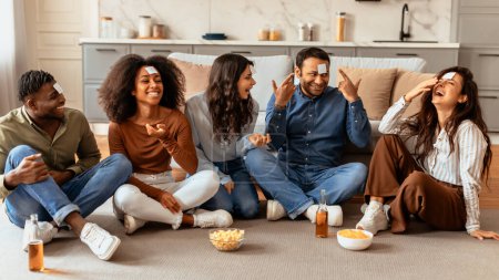 Eine fröhliche Gruppe multiethnischer Freunde führt ein unbeschwertes Gespräch und zeigt echtes Lachen und Trost beim Spielen