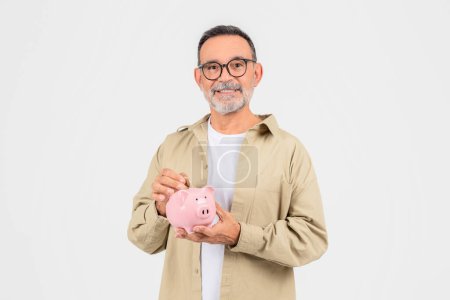 An older man with a beard shows a pink piggy bank suggesting themes of savings, retirement, and financial planning