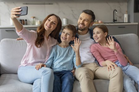 Quatre membres de la famille père mère et enfants prendre un selfie ensemble sur un canapé avec des expressions gaies
