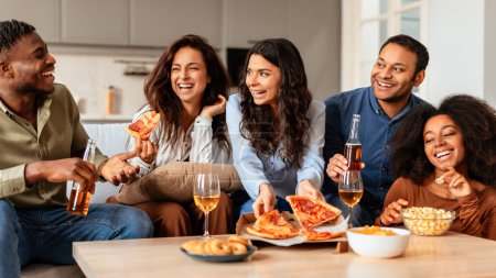 A cheerful group of multiracial friends enjoys a casual gathering with drinks and snacks, sharing laughter and good times