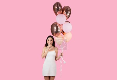 Photo for Lady with a finger on her lips, holding a bunch of balloons, set against a European summer-inspired backdrop, suitable for generation z, isolated - Royalty Free Image