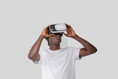 Tourné de gars afro-américain absorbé dans la mise en place d'un casque VR, soulignant l'intégration de la technologie de pointe dans la vie quotidienne et le divertissement