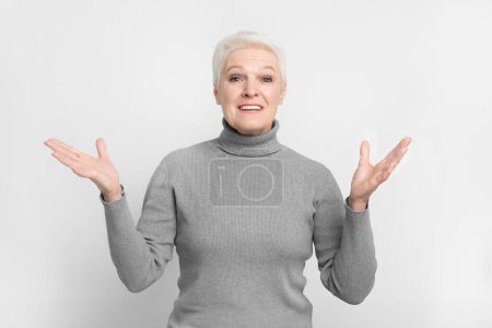Photo for A senior european woman in a gray turtleneck looks puzzled, perfect for s3niorlife themes conveying confusion - Royalty Free Image