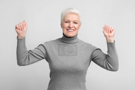 Téléchargez les photos : Femme européenne âgée joyeuse jette ses poings vers le haut dans une pose de victoire, image idéale pour s3niorlife promotions - en image libre de droit