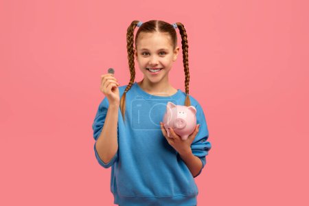A cheerful girl holding a piggy bank and coin, representing saving and financial education on a pink background