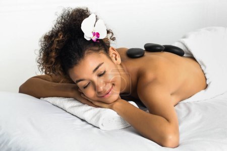 Téléchargez les photos : Massage de pierre. Femme relaxante au salon de spa avec les yeux fermés - en image libre de droit