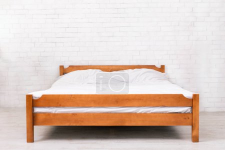 Photo for Bedroom interior. Empty wooden framed double bed with two pillows and white blanket, free space. Real photo. - Royalty Free Image
