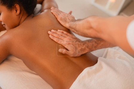 Photo for Close-up view of a back massage for African American lady, showcasing the hands technique on the skin - Royalty Free Image