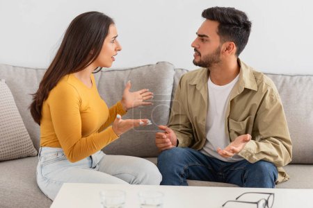 Paar in einem Gespräch, während es auf einem Sofa im Beratungsbüro sitzt, scheinbar in einem Gespräch oder Streit