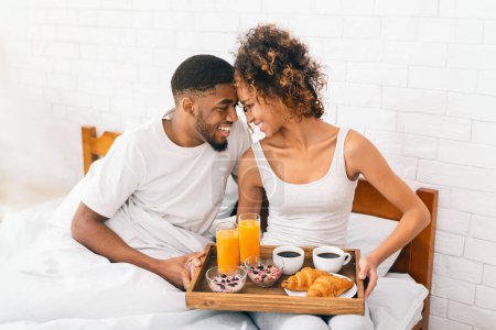 Téléchargez les photos : Heureux couple afro-américain amoureux profitant du petit déjeuner au lit, belle matinée - en image libre de droit
