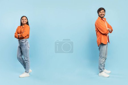 Confident Indian man and woman standing back-to-back with crossed arms in orange shirts and jeans, copy space