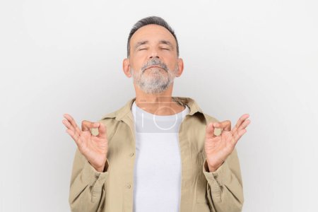 Ruhiger älterer Mann mit Bart, der friedlich meditiert, Augen geschlossen in Zen-Relax-Pose auf weißem Hintergrund