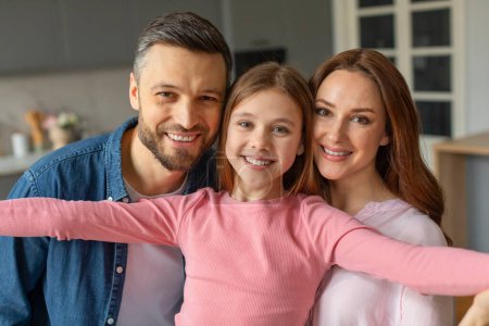 Familia sonriente con los padres y la niña en un ambiente cálido hogar que muestra afecto y felicidad
