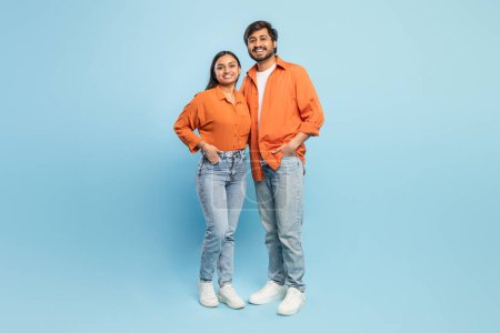 Relaxed Indian man and woman loving couple standing side by side in casual wear on a blue background