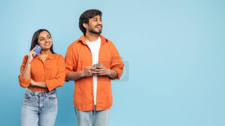 Foto de Hombre y mujer indios sosteniendo un teléfono inteligente y tarjeta de crédito, buscando esperanzado o reflexivo sobre una decisión financiera - Imagen libre de derechos