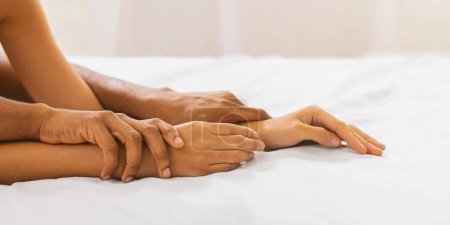 Des jeux sexuels. Mains de couple afro-américain faisant l'amour au lit, panorama, espace libre

