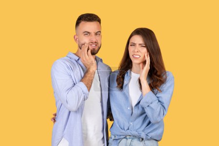 Un homme grimaçant touche sa joue et une femme tient sa mâchoire indiquant des maux de dents ou des douleurs dentaires