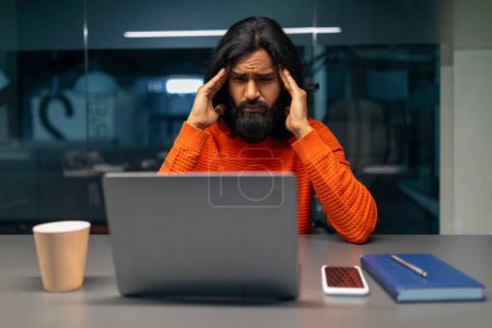 Foto de Hombre ansioso que experimenta estrés mientras trabaja en el ordenador portátil, mostrando las manos en la cabeza - Imagen libre de derechos