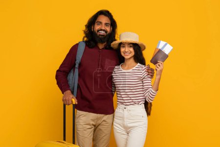 Aufgeregtes Paar bereit für die Reise mit Gepäck, Reisepass und Tickets, die auf gelbem Hintergrund stehen