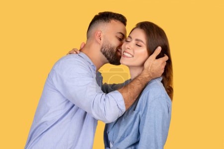 Un geste d'amour d'un homme embrassant une femme sur sa joue, dépeignant affection et tendresse sur fond jaune