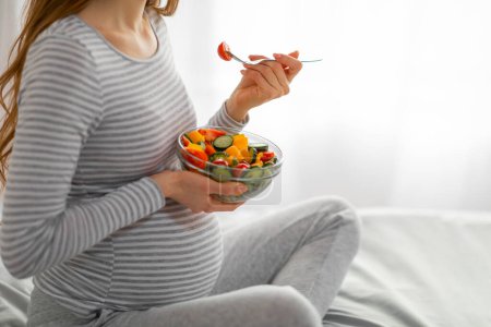 Photo captures a pregnant woman indulging in a healthy salad, highlighting the importance of diet for expectant mothers