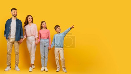 Téléchargez les photos : Famille avec enfants pointant et regardant de côté sur un fond jaune, espace de copie, grande offre - en image libre de droit