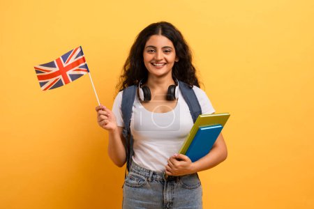 Selbstbewusste junge Studentin mit britischer Flagge und Notizbüchern als Symbol für internationale Bildung