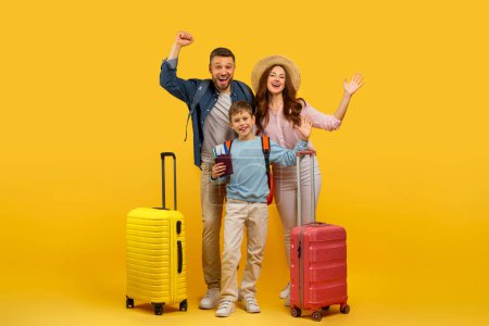 Téléchargez les photos : Une famille joyeuse avec des valises posant avec enthousiasme sur un fond jaune, mettant en valeur l'excitation pour les voyages - en image libre de droit