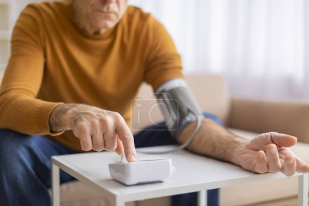 Foto de Un hombre maduro está comprobando su presión arterial, ilustrando la conciencia de salud y la importancia de un monitoreo regular - Imagen libre de derechos