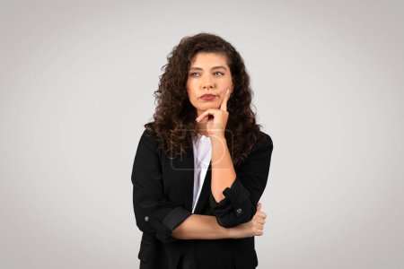 Foto de Mujer pensativa en ropa de negocios con la barbilla apoyada en su mano, mostrando consideración - Imagen libre de derechos