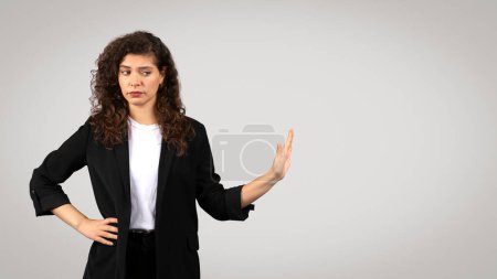 Woman in businesswear showing skepticism with a dismissing hand gesture