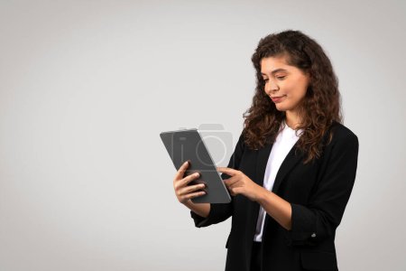 Businesswoman engaged with a digital tablet, possibly reviewing reports or browsing