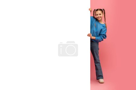 Foto de Chica alegre con coletas sosteniendo una pizarra blanca en blanco sobre un fondo rosa dual, espacio de copia maqueta para el anuncio - Imagen libre de derechos