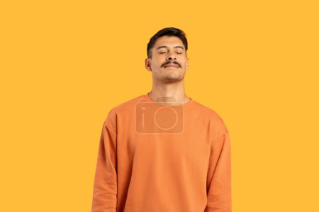 Photo for A relaxed man with eyes closed and head tilted upward against a vibrant yellow background, exuding tranquility - Royalty Free Image